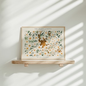 May include: A framed print with a white background featuring a deer with antlers surrounded by white daisies and green leaves. The text "THE SECRET GARDEN" and "HEATHER BAITY" is at the top of the print. The text "You've got a secret of gold." is at the bottom of the print.