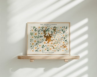 May include: A framed print with a white background featuring a deer with antlers surrounded by white daisies and green leaves. The text "THE SECRET GARDEN" and "HEATHER BAITY" is at the top of the print. The text "You've got a secret of gold." is at the bottom of the print.