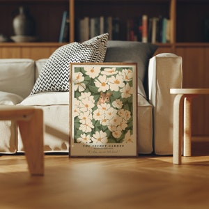 Pode incluir: Uma impressão emoldurada de uma ilustração de flores brancas com um pequeno esquilo espiando por trás das flores. O texto "THE SECRET GARDEN" está na parte inferior da impressão, juntamente com as palavras "SEVEN-SISTERS ROSE" e "It's alay, my cute little friend."