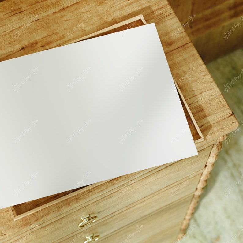 May include: A wooden dresser with a white sheet of paper on top of the open drawer. The dresser has a rope-like design on the side and gold-colored handles on the drawers.