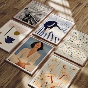 Könnte beinhalten: Eine Sammlung gerahmter Kunstdrucke mit verschiedenen Kunststilen. Die Drucke zeigen eine Person, abstrakte Formen, florale Muster und ein berühmtes expressionistisches Kunstwerk. Die Rahmen sind aus Holz, und die Kunst wird auf einer Holzoberfläche präsentiert.