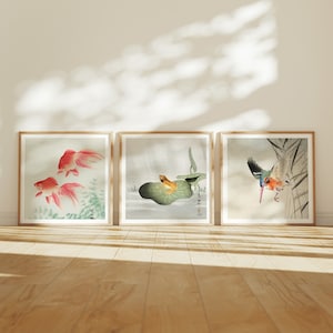 Può includere: Tre stampe incorniciate con opere d'arte di ispirazione giapponese. La prima stampa presenta due pesci rossi che nuotano in uno stagno. La seconda stampa mostra una rana seduta su una ninfea verde. La terza stampa raffigura un martin pescatore blu e arancione appollaiato su un ramo.