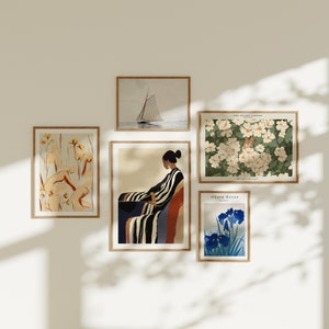 Peut inclure: Cinq impressions d'art encadrées sur un mur blanc. Les impressions représentent un voilier, une femme en robe rayée, un motif floral, un motif floral avec un petit animal et une fleur bleue.