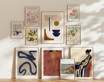 May include: A collection of framed art prints displayed on a wall. The prints feature various abstract designs, floral illustrations, and portraits. Some prints include text such as "FLEURS" and "OHARA KOSON". The frames are a mix of sizes and styles.