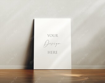 Könnte beinhalten: Ein weißer Leinwand-Mockup mit dem Text "YOUR Design HERE" in minimalistischem Stil, der auf einem Holzboden vor einer weißen Wand steht.