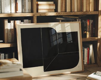 May include: A framed abstract art print featuring a bold black geometric design on a cream background. The artwork is displayed on a wooden floor in front of a bookshelf filled with books. The frame is a light wood color.