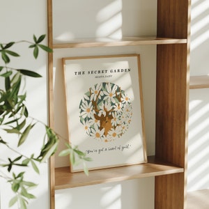 May include: A framed print with a white background and a deer surrounded by white daisies. The text "THE SECRET GARDEN" and "SHASTA DAISY" is at the top of the print. The text "You've got a heart of gold." is at the bottom of the print.