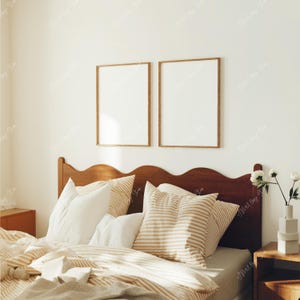 May include: A wooden bed frame with a wavy headboard and a beige and white striped duvet cover. There are two framed pictures above the headboard, and a vase of white flowers on a small wooden table next to the bed.