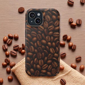 May include: A smartphone case featuring a close-up pattern of roasted coffee beans. The case is black with a dual-lens camera cutout. Scattered coffee beans surround the case on a light brown wooden surface and a burlap sack.