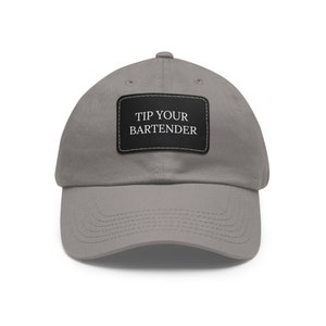 May include: A gray baseball cap with a black patch that says "TIP YOUR BARTENDER" in white text.