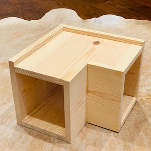 May include: A wooden corner shelf with three open compartments. The shelf is made of natural wood and has a simple, rustic design.