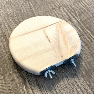 May include: A round wooden perch with two metal screws and washers attached to the bottom. The perch is made of light wood and has a smooth surface.