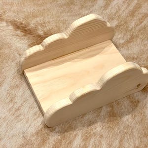 May include: A wooden shelf shaped like a cloud, made of natural light wood. The shelf is empty and ready to be decorated.
