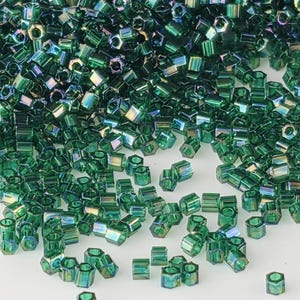 May include: A collection of small, hexagonal-shaped glass beads in a vibrant emerald green color. Each bead features a translucent finish with an iridescent, metallic sheen that reflects light, creating a multi-faceted appearance across the surface.