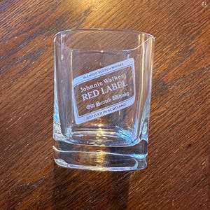 K&ouml;nnte beinhalten: Ein klares Glas mit einem Johnnie Walker Red Label Scotch Whisky-Etikett. Das Etikett ist wei&szlig; mit roten und schwarzen Buchstaben. Auf dem Etikett steht "Blended Scotch Whisky", "Johnnie Walker", "Red Label" und "Old Scotch Whisky". Au&szlig;erdem steht auf dem Etikett "Abgef&uuml;llt in Schottland".