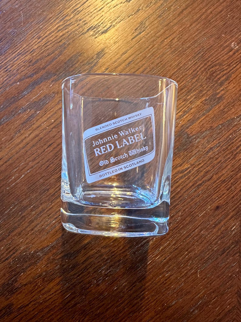 K&ouml;nnte beinhalten: Ein klares Glas mit einem Johnnie Walker Red Label Scotch Whisky-Etikett. Das Etikett ist wei&szlig; mit roten und schwarzen Buchstaben. Auf dem Etikett steht "Blended Scotch Whisky", "Johnnie Walker", "Red Label" und "Old Scotch Whisky". Au&szlig;erdem steht auf dem Etikett "Abgef&uuml;llt in Schottland".
