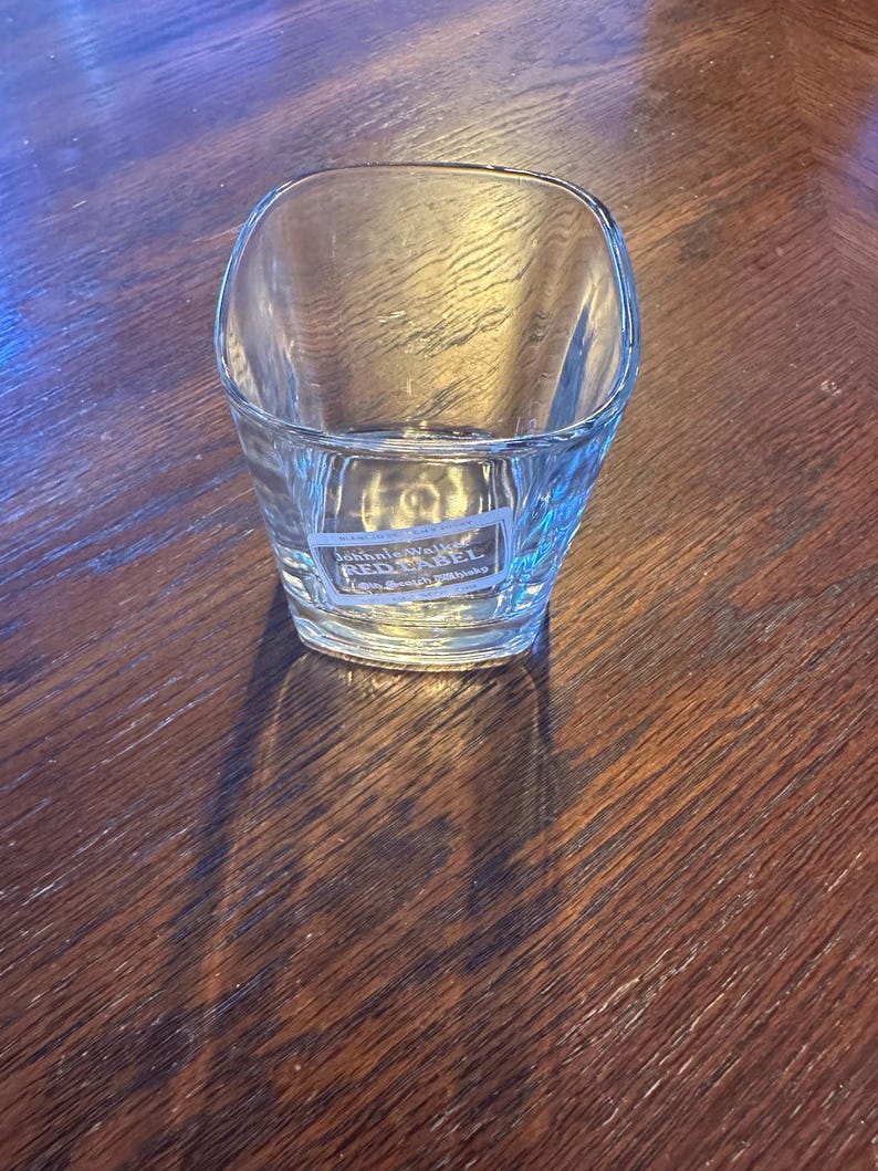 K&ouml;nnte beinhalten: Ein klares Glas mit quadratischem Boden und einem John Walker & Sons Red Label Scotch Whisky Logo auf der Unterseite.