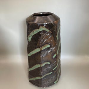 May include: A trio of cream-glazed ceramic mugs, each adorned with a hand-painted floral pattern in blue, green, and yellow hues. The mugs have a rounded form and a handle, perfect for tea or coffee. Each mug is approximately 10cm tall.