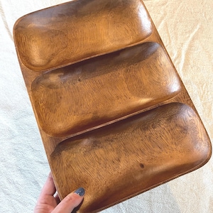 May include: A rectangular wooden serving tray with three compartments. The tray is made of light brown wood with visible grain patterns. The compartments are rectangular with rounded corners.