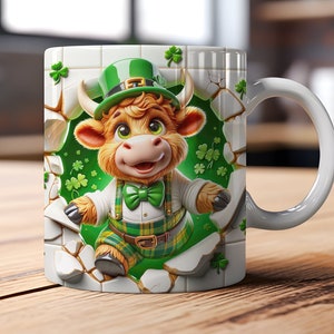Könnte beinhalten: Eine weiße Keramiktasse mit einem grünen, weißen und braunen Cartoon-Stier, der einen grünen Hut und einen grünen und karierten Kilt trägt. Der Stier schaut aus einer rissigen Wand mit grünen Kleeblättern.
