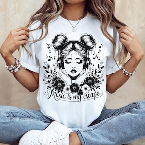 Peut inclure: T-shirt blanc avec un motif noir et blanc d'une femme portant un casque, entourée d'éléments floraux et de notes de musique. Le texte "Music is my escape" est écrit en dessous.