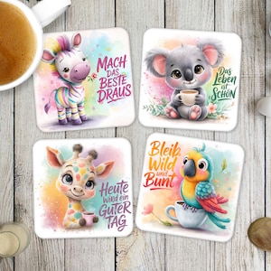 May include: A set of four square coasters with watercolour illustrations of cute animals. Each coaster features a different animal: a zebra, koala, giraffe, and parrot, each holding a cup. Each coaster has a different German phrase.