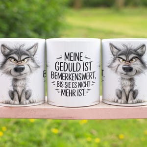 May include: Three white ceramic mugs with a humorous wolf illustration. The wolf has gray fur and an angry expression. The middle mug has the German text "MEINE GEDULD IST BEMERKENSWERT, BIS SIE ES NICHT MEHR IST."