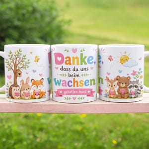 Könnte beinhalten: Drei weiße Keramikbecher mit farbenfrohen Waldtierdesigns. Ein Becher zeigt einen Baum, einen Igel, ein Kaninchen und einen Fuchs. Ein weiterer Becher hat den Text "Danke, dass du uns beim wachsen geholfen hast". Der dritte Becher zeigt ein Reh, einen Bären und einen Waschbären.