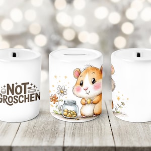 Può includere: Salvadanai in ceramica bianca con una fessura sulla parte superiore. Un lato presenta un criceto dei cartoni animati che tiene in mano una moneta accanto a un barattolo di monete e fiori. L'altro lato ha il testo "NOT GROSCHEN".