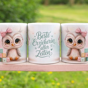 Könnte beinhalten: Drei weiße Keramikbecher mit einem Eulen-Design. Jeder Becher zeigt eine Cartoon-Eule mit Brille und rosa Schleife. Der mittlere Becher hat den Text "Beste Erzieherin aller Zeiten". Die Becher stehen auf einer rosa Oberfläche.