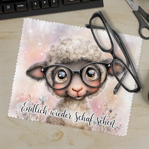 Pode incluir: Um tapete de rato com uma ovelha de desenho animado usando óculos, com o texto alemão "Endlich wieder Schaf Sehen". O tapete tem uma borda ondulada e é decorado com flores. Um par de óculos pretos repousa sobre o tapete.
