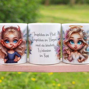 Op de afbeelding: Drie witte keramische mokken met cartoon illustraties. Eén mok toont een duivels meisje met hoorns, een andere heeft tekst en de derde toont een engelachtig meisje met een halo. De mokken staan op een roze oppervlak.