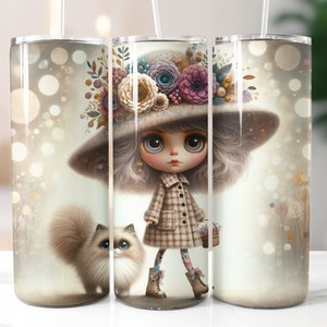 Op de afbeelding: Een roestvrijstalen tumbler met een fantasierijke illustratie van een meisje met grote ogen dat een bloemenkrans en een geruite jurk draagt. Het meisje houdt een mand met bloemen vast en een kleine kat zit naast haar. De achtergrond is zacht lichtbruin met een bokeh-effect.