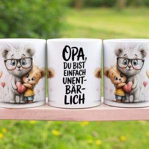 Könnte beinhalten: Weiße Keramikbecher mit einer niedlichen Bärenillustration, die eine Brille trägt und einen kleineren Bären umarmt, der ein Herz hält. Der mittlere Becher trägt den deutschen Text "Opa, du bist einfach unentbärlich."