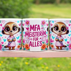 May include: White ceramic mug featuring a cartoon meerkat in a pink medical coat, holding a syringe. The mug is decorated with flowers, hearts, and the text "MFA-MEISTERIN FÜR ALLES". The design includes a stethoscope and a pill.
