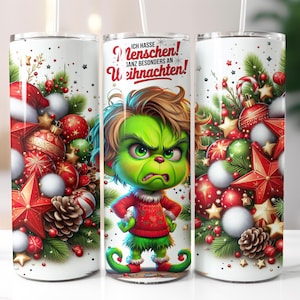 May include: A white tumbler featuring a green Grinch character and the text "Ich hasse Menschen! Ganz besonders an Weihnachten!" surrounded by red and green Christmas decorations.