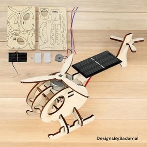 Könnte beinhalten: Ein Holz-Helikopter-Bausatz mit Solarpanel, Motor und Anleitung. Der Bausatz ist aus Naturholz gefertigt und bereit zum Zusammenbauen.