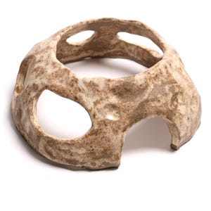 May include: A handcrafted, ceramic bowl with a unique, organic shape. The bowl is a light brown colour with darker brown speckles, and features three large openings. The bowl is designed with a textured surface.