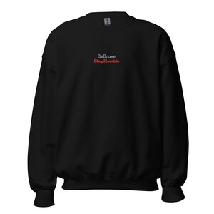 Könnte beinhalten: Schwarzer Pullover mit dem Text "Be Brave Stay Humble" in weißer und roter Schrift.