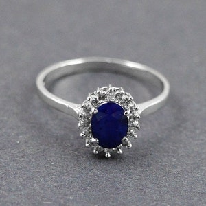 May include: A silver ring with a large oval blue sapphire surrounded by smaller clear stones.