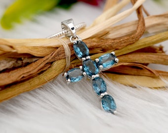 Puede incluir: Un colgante de cruz de plata con siete piedras de topacio azul ovaladas.