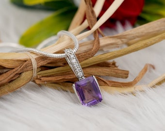 May include: A silver chain necklace with a square-shaped amethyst pendant surrounded by small clear diamonds.