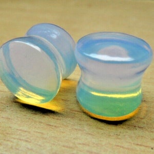May include: Two iridescent blue and white glass ear gauges. The gauges are round and have a smooth, polished finish.