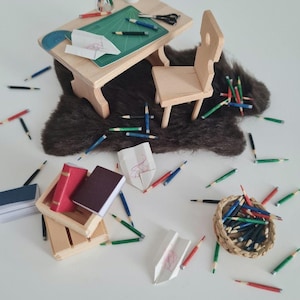 Peut inclure: Un bureau miniature en bois avec un tapis de coupe vert, une tasse de café et une chaise. Il y a des crayons, du papier et des livres éparpillés autour du bureau.