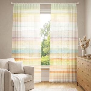 May include: Sheer window curtains with a watercolor stripe design in pastel colors of yellow, green, blue, purple, and orange. The curtains hang in front of a window with a view of trees. A beige sofa and wooden dresser are in the room.