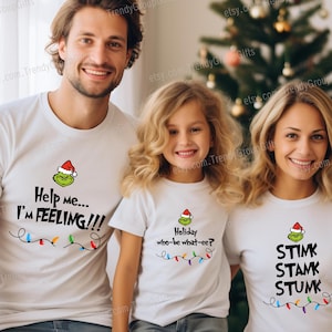 May include: Three people wearing white t-shirts with Grinch-themed designs. The shirts have text that reads "Help me... I'm FEELING!!!", "Holiday who-be what-ee?", and "STIMK STAMK STUMK". The image is labeled "GROUP CHRISTMAS (30+ Quotes)".
