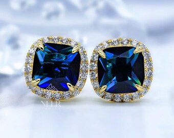 Pendientes de botón con halo de zafiro azul en forma de cojín y detalles de moissanita en oro de 14 quilates.