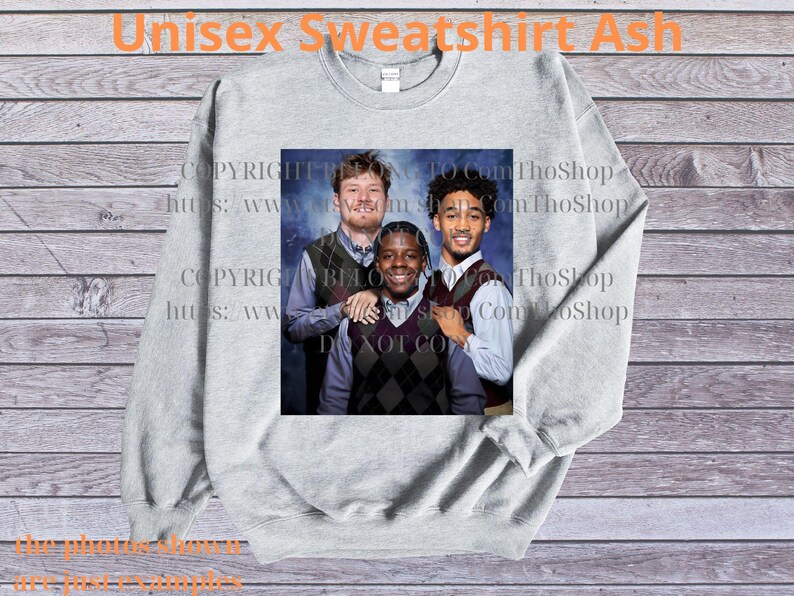 May include: A light gray unisex sweatshirt with a graphic of three people. The sweatshirt has the text "Unisex Sweatshirt Ash" at the top. The graphic is a portrait of three people wearing argyle vests and button-down shirts.