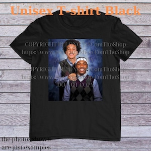 May include: Black unisex t-shirt featuring a photograph of two people. The photograph shows two people wearing argyle vests over collared shirts. The text "Unisex T-shirt Black" is at the top. The text "the photos shown are just examples" is at the bottom.