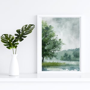 May include: A framed watercolor painting of a lake scene with a large tree in the foreground and a misty background. The painting is in shades of green, blue, and gray.